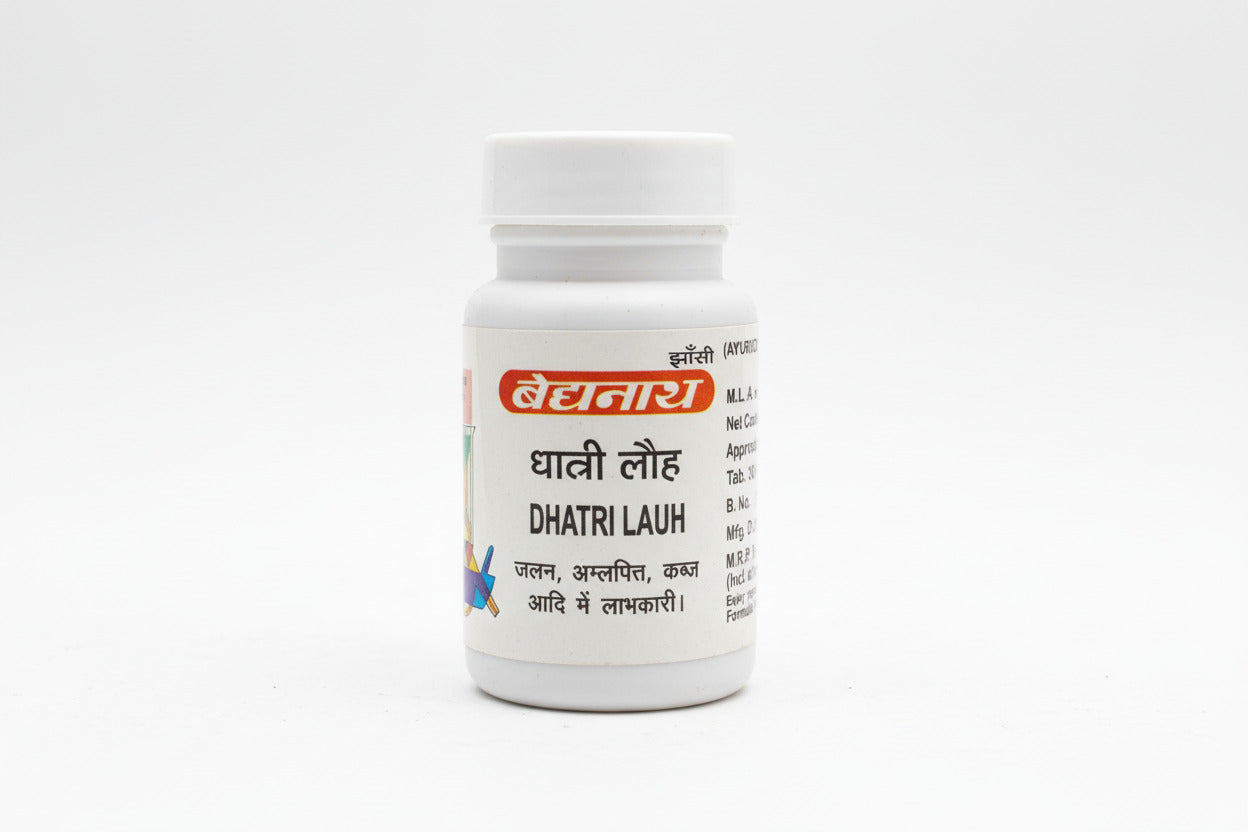 Small white bottle labeled 'Dhatri Lauh' held by a hand on a wooden surface.