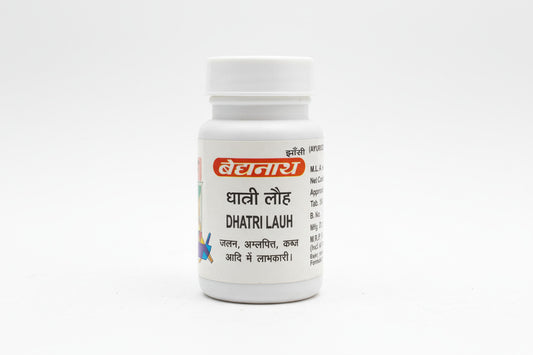 Small white bottle labeled 'Dhatri Lauh' held by a hand on a wooden surface.