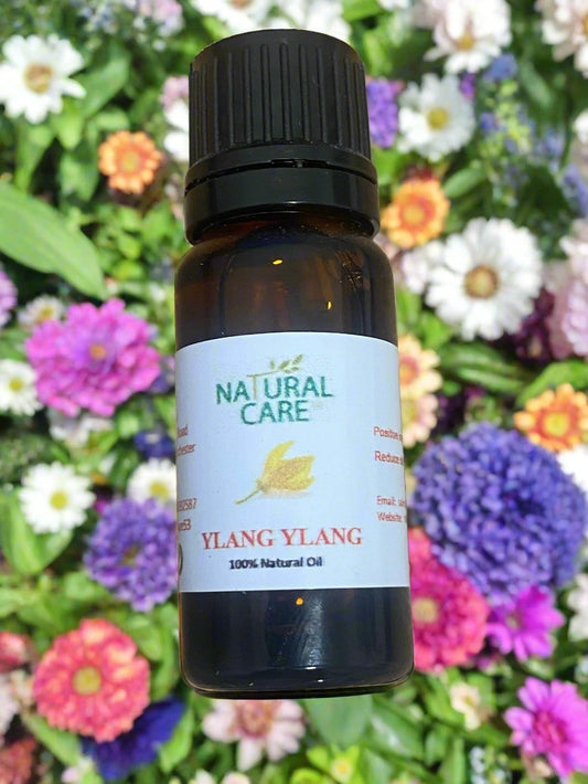 Bottle of Ylang Ylang essential oil with 'Natural Care' label on a wooden surface
